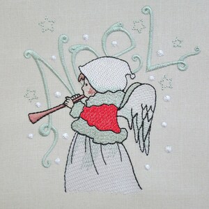May include: Embroidered design of an angel playing a flute with a white dress and red sash, surrounded by stars and the word "Noel" in cursive.
