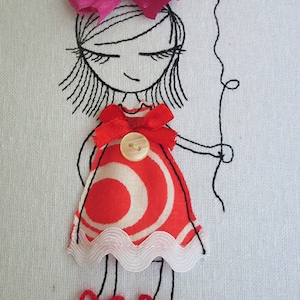 以下が含まれることがあります： 赤いハート型の風船を持った、赤と白のドレスを着た女の子の刺繍イラスト。ピンクのリボンを髪につけ、赤い靴にはリボンがついています。