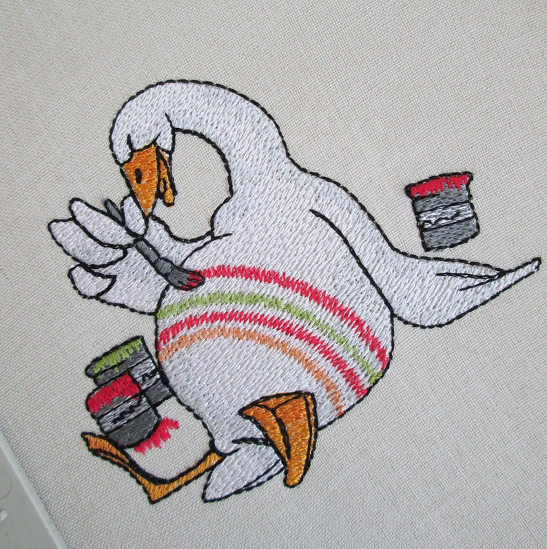 Op de afbeelding: Borduurwerk van een witte gans die een kwast vasthoudt en naast twee verfpotten staat. De gans heeft een rood-oranje-groen gestreept patroon op zijn lichaam.