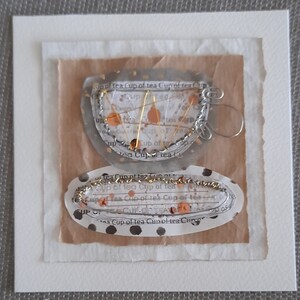 Wire Cup of Tea. An original handmade mixed media artwork made from silver and gold coloured wire on paper in grey and white tones.