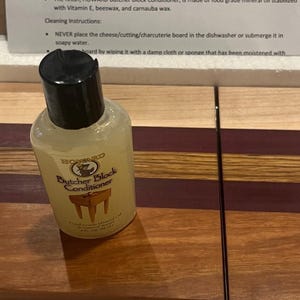 May include: A clear plastic bottle of Howard Butcher Block Conditioner. The bottle has a black cap and a label with the product name and instructions for use.