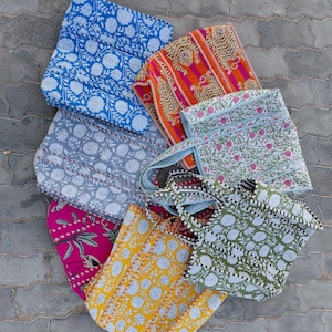 May include: A collection of patterned tote bags in various colours. The bags feature floral and geometric designs in shades of blue, orange, pink, yellow, and green. Each bag has a unique print, with white floral patterns on some.