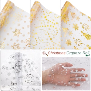 May include: Three rolls of sheer white organza fabric with gold foil designs. The designs include snowflakes, stars, and Christmas trees. The fabric is perfect for wrapping gifts, decorating crafts, or adding a touch of sparkle to any project.