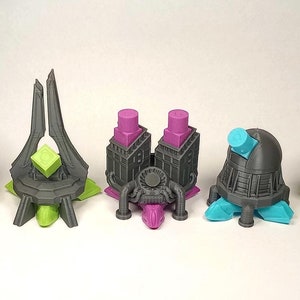 Op de afbeelding: Een verzameling van vijf futuristische, abstracte sculpturen in grijstinten, geel, groen, paars en turquoise. Elke sculptuur heeft een uniek ontwerp met geometrische vormen en architecturale elementen. De objecten zijn 3D-geprint.