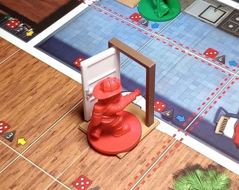 May include: A board game called "Flash Point" with a red and green figurine on the game board. The game board has a red and white checkered pattern and features a house with a kitchen, dining room, and living room. The game board also has a fire extinguisher and a hose.