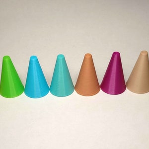 以下が含まれることがあります： 銀、銅、金、緑、青、茶色、ピンクなど、さまざまな色の小さな円錐形のオブジェクトが12個並んでいます。