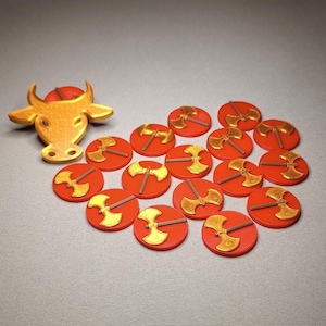 May include: A gold bull head figurine surrounded by 15 red and gold ax-shaped tokens.