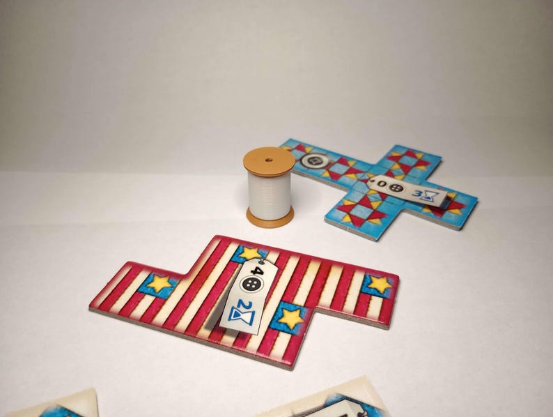 May include: A wooden cotton reel and several game pieces. The game pieces are in the shape of a cross and a flag, with red and white stripes, blue stars, and tags with numbers and symbols.