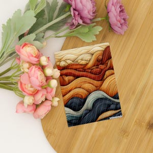 May include: A rectangular print featuring an abstract design of flowing, layered lines in shades of cream, orange, rust, and dark blue, accompanied by a cluster of pink artificial flowers with green stems and leaves.