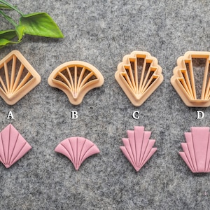 May include: Set of ten cookie cutters in two colours, beige and pink. The cutters are shaped like geometric designs, including a diamond, fan, and scallop. The cutters are arranged in two rows of five, with the beige cutters on top and the pink cutters on the bottom.