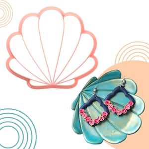 Può includere: Un tagliabiscotti rosa a forma di conchiglia accanto a un paio di orecchini blu scuro con accenti di rose rosa. Gli orecchini sono su un espositore turchese a forma di ventaglio. Sfondo bianco con forme geometriche pastello.