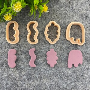 Puede incluir: Conjunto de ocho cortadores de galletas, seis de madera y dos de color rosa. Los cortadores de madera tienen forma de línea ondulada, nube, fantasma, círculo, corazón y flor. Los cortadores de color rosa tienen forma de línea ondulada, nube y fantasma.