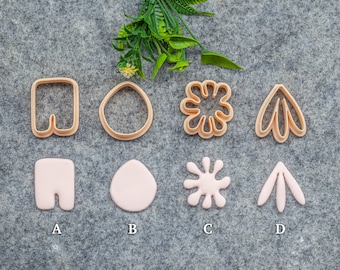 May include: Four cookie cutters in the shape of a pair of pants, an egg, a flower, and a leaf. Below the cutters are four pink fondant shapes made with the cutters.