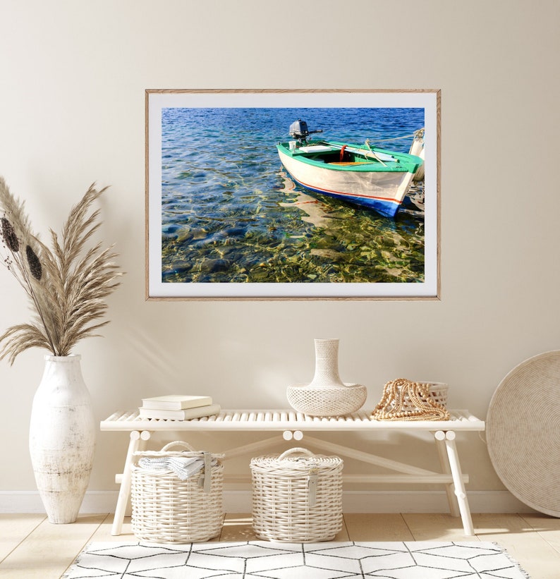 K&ouml;nnte beinhalten: Ein wei&szlig;es Holzboot mit gr&uuml;nen und blauen Akzenten liegt in klarem, blauem Wasser vor Anker. Das Wasser ist flach und man kann die Felsen und den Sand am Grund sehen. Das Boot hat einen kleinen Motor am Heck.