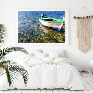 K&ouml;nnte beinhalten: Ein wei&szlig;es und gr&uuml;nes Holzboot mit einem kleinen Au&szlig;enbordmotor liegt in klarem, blauem Wasser vor Anker. Das Wasser ist flach und der Grund ist mit Steinen und Seegras sichtbar.