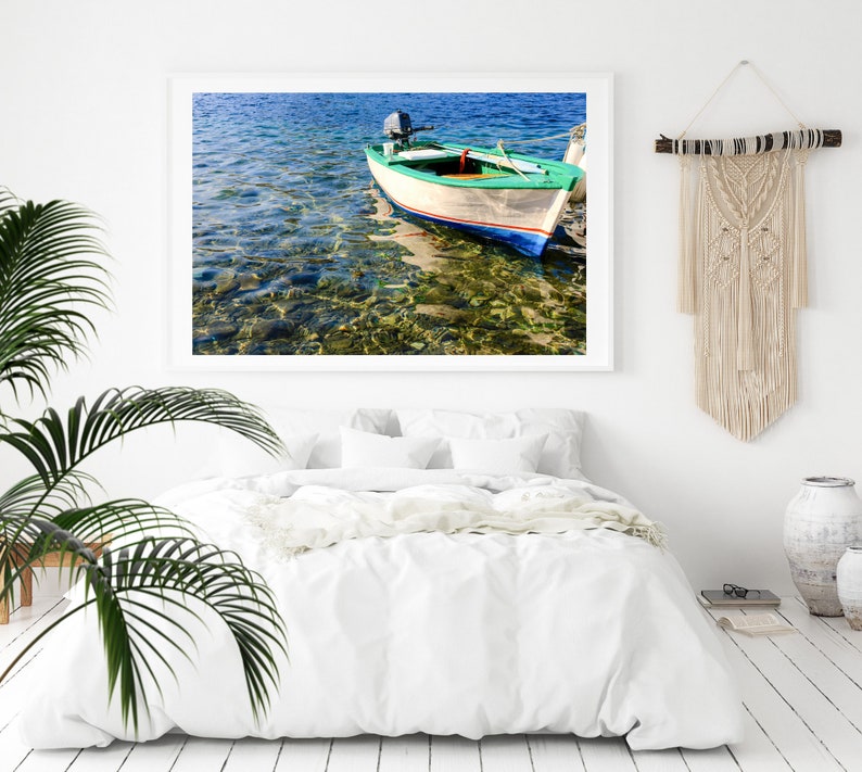 K&ouml;nnte beinhalten: Ein wei&szlig;es und gr&uuml;nes Holzboot mit einem kleinen Au&szlig;enbordmotor liegt in klarem, blauem Wasser vor Anker. Das Wasser ist flach und der Grund ist mit Steinen und Seegras sichtbar.