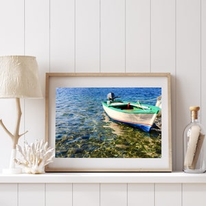 K&ouml;nnte beinhalten: Ein gerahmtes Foto eines kleinen, gr&uuml;n-wei&szlig;en Bootes mit einem Au&szlig;enbordmotor, das in klarem, blauem Wasser schwimmt. Das Wasser ist flach und der Grund ist sichtbar, mit Felsen und Seegras.