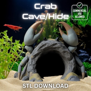 May include: A gray crab-shaped cave/hide for aquariums. The cave has large claws with brown tips and a large opening. The text "Crab Cave/Hide" is above the cave, and "STL DOWNLOAD" is below. A red shrimp and aquatic plants are in the background.