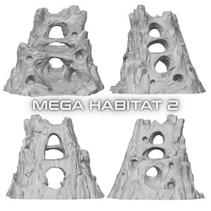 May include: Four gray, textured, rock-like structures with various openings and tunnels. The structures are arranged in a square formation. The text "MEGA HABITAT 2" is displayed in a white, bold font below the structures.
