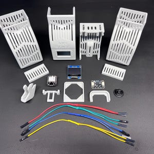 Puede incluir: Un surtido de componentes electr&oacute;nicos blancos impresos en 3D, que incluyen carcasas ranuradas, placas de circuito, una peque&ntilde;a pantalla y varios conectores. Tambi&eacute;n hay varios cables multicolores, lo que sugiere un proyecto o kit.