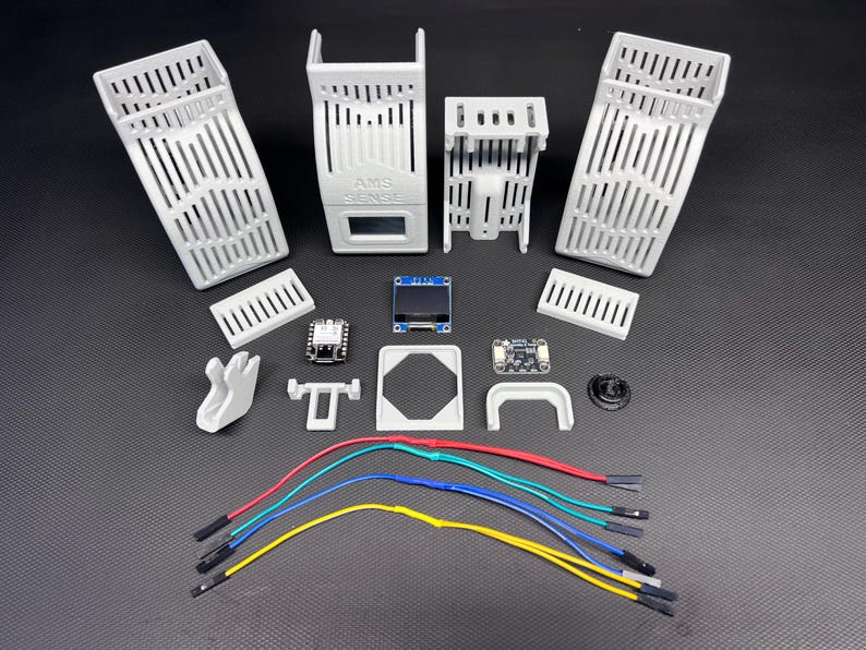Puede incluir: Un surtido de componentes electr&oacute;nicos blancos impresos en 3D, que incluyen carcasas ranuradas, placas de circuito, una peque&ntilde;a pantalla y varios conectores. Tambi&eacute;n hay varios cables multicolores, lo que sugiere un proyecto o kit.