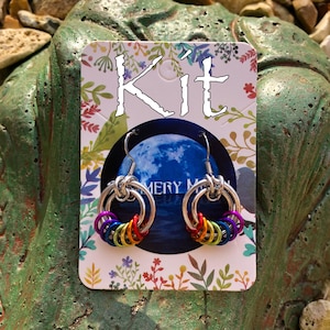 Może przedstawiać: Zestaw do tworzenia tęczowych kolczyków. Zestaw zawiera wszystkie niezbędne materiały, w tym drut, koraliki i elementy zapięcia. Kolczyki są wykonane techniką zwaną "chainmaille".