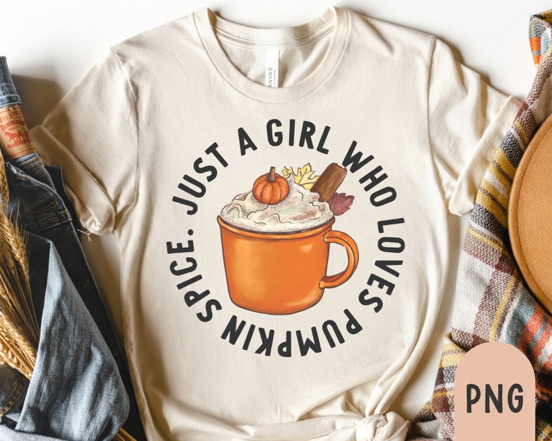 May include: Cream-colored t-shirt featuring a circular graphic of a pumpkin spice latte with a pumpkin, cinnamon stick, and leaves. The text reads "Spice. Just a girl who loves pumpkin."