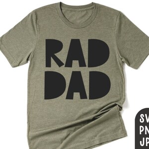 Può includere: T-shirt verde oliva con le parole "RAD DAD" in grassetto nero. La maglietta ha un girocollo e maniche corte. Una piccola grafica con "SVG PNG JPG" si trova nell'angolo in basso a destra.