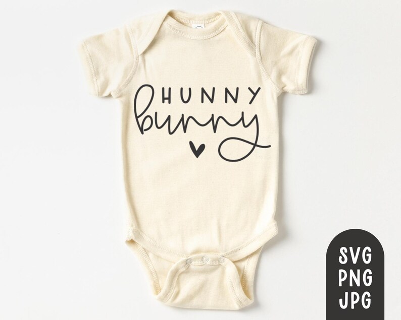 K&ouml;nnte beinhalten: Cremefarbener Baby-Body mit den Worten "HUNNY bunny" in schwarzer Schrift, einem kleinen schwarzen Herz und einem Druckknopfverschluss. Der Body hat kurze &Auml;rmel und einen runden Halsausschnitt. Eine schwarz-wei&szlig;e Grafik mit "SVG PNG JPG" befindet sich unten rechts.