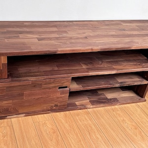 May include: A dark brown wooden entertainment center with a long top shelf, a pull-out drawer, and three open shelves.