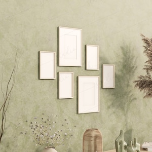 May include: Five simple wooden frames with white mounts are arranged on a green wall. The frames are empty and ready for photos or artwork. A dried grass plant is in the corner of the image.