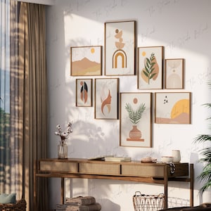 Puede incluir: Un conjunto de ocho impresiones de arte de pared minimalistas con formas y diseños abstractos en tonos marrones, beige y amarillos. Las impresiones están dispuestas en una cuadrícula en una pared blanca sobre una mesa consola de madera con una parte superior de ratán tejido.