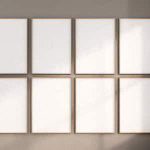 Puede incluir: Ocho marcos de fotos dorados están dispuestos en una cuadrícula en una pared beige. Los marcos están vacíos y listos para fotos u obras de arte.