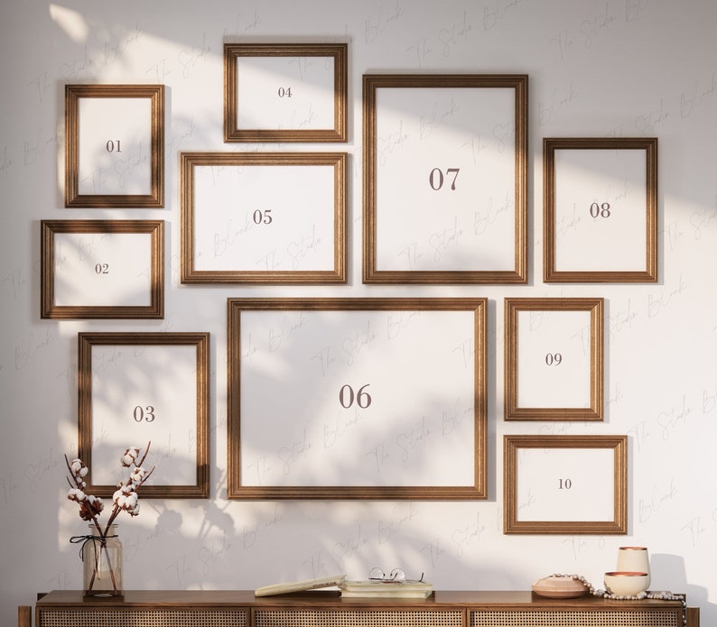 May include: Ten gold picture frames of various sizes are arranged on a white wall. The frames are numbered 1 through 10. The frames are all empty.
