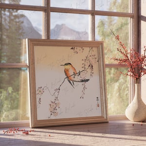 May include: A framed print of a bird perched on a branch of a flowering tree. The bird is orange, yellow, and brown with a long tail. The background is a light beige color. The print is in a wooden frame with a white mat.