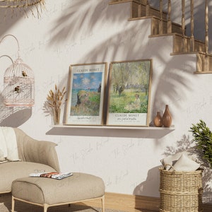 May include: Two framed art prints of Claude Monet paintings, one depicting a landscape with a river and trees, the other a seascape with a rocky shore. The prints are displayed on a shelf with a small birdcage and a vase of dried flowers.