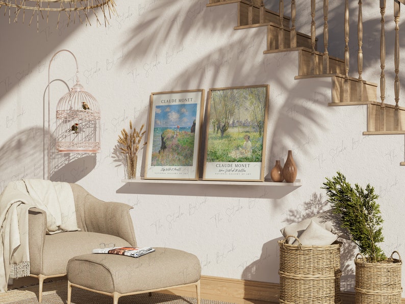 May include: Two framed art prints of Claude Monet paintings, one depicting a landscape with a river and trees, the other a seascape with a rocky shore. The prints are displayed on a shelf with a small birdcage and a vase of dried flowers.