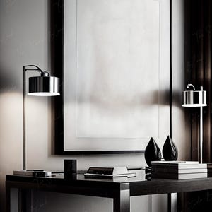 May include: A black desk with a black chair, two lamps, and a large framed picture. The desk has a black surface and a black frame. The chair has a black seat and a black back. The lamps have black bases and black shades. The picture has a black frame and a white background.