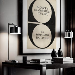 May include: Black and white graphic print with the text "BALANCE is not SOMETHING YOU FIND, it is SOMETHING YOU CREATE". The print is framed and hanging on a wall above a black desk.