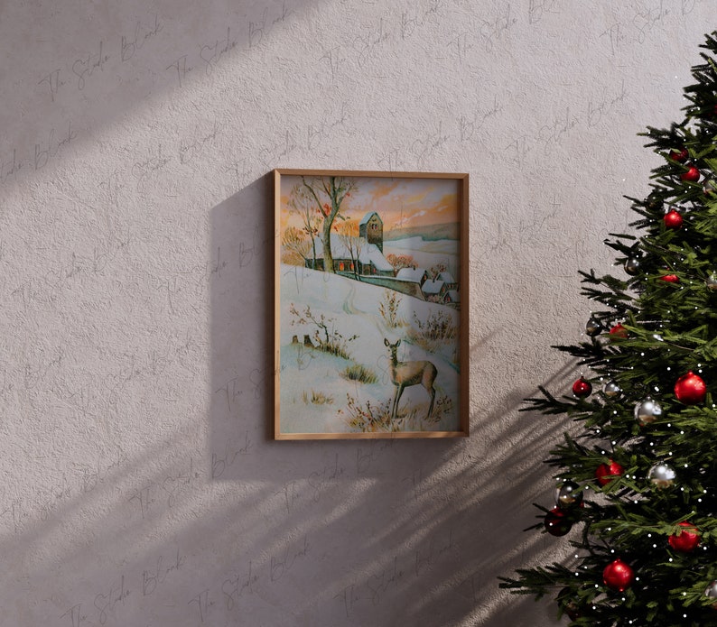 May include: A framed vintage illustration of a snowy winter scene with a small village, a deer, and a church in the distance. The illustration is in a wooden frame and is hanging on a wall.