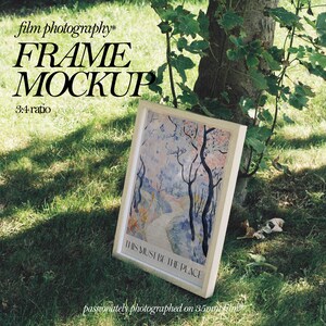 May include: A white frame with a 3:4 ratio, sitting on green grass. The frame contains a watercolor painting of a path through a forest with the text "THIS MUST BE THE PLACE" printed on the bottom. The text "film photography* FRAME MOCKUP 3:4 ratio passionately photographed on 35mm film" is printed below the frame.