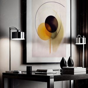 May include: A black framed abstract painting with a white background and three overlapping circles in shades of yellow, green, and purple. The painting is hanging on a wall above a black desk with a lamp and two decorative objects.