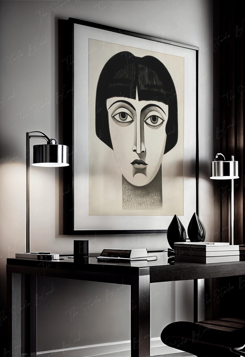 May include: A black and white illustration of a woman's face with a short bob haircut. The illustration is framed and hanging on a wall above a black desk with two lamps and a stack of books.