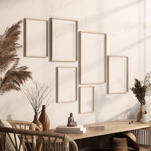 Może przedstawiać: Wnętrze salonu z drewnianym stołem, wiklinowym krzesłem i pięcioma pustymi ramkami na zdjęcia na ścianie. Ramki są ułożone w sposób schodkowy. Na stole znajdują się suszone rośliny i mały posążek.