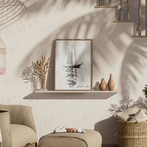 May include: A framed black and white watercolor painting of a sailboat on the water with the text "Windless Home" at the bottom. The painting is on a white shelf with two decorative vases and a vase with dried wheat.