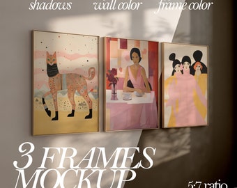 May include: Three framed art prints with different images. The first print features a cat with a scarf, the second print features a woman sitting at a table, and the third print features three women standing together. The frames are all gold and the prints are all in a 5:7 ratio.