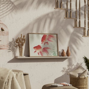 May include: A framed print of two red goldfish swimming in a light blue and green water setting. The print is on a white shelf with two small brown vases and a vase with dried wheat stalks. The shelf is against a white wall with a birdcage hanging above it.