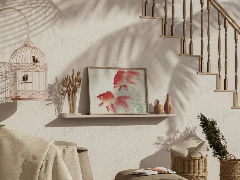 May include: A framed print of two red goldfish swimming in a light blue and green water setting. The print is on a white shelf with two small brown vases and a vase with dried wheat stalks. The shelf is against a white wall with a birdcage hanging above it.