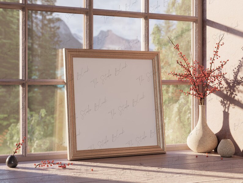 May include: A gold-toned picture frame with a white mat and a blank white canvas inside. The frame is sitting on a wooden surface next to a vase with red berries and a smaller vase.