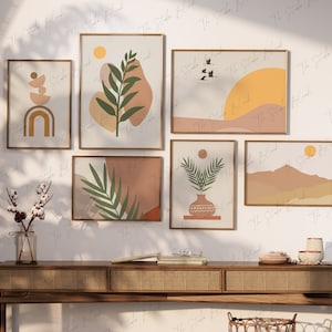 Op de afbeelding: Zes ingelijste abstracte kunstprints met een boho-thema. De prints tonen verschillende vormen, kleuren en patronen, waaronder een zon, palmbladeren en bergen. De prints zijn in een rasterpatroon op een witte muur boven een houten consoletafel gerangschikt.